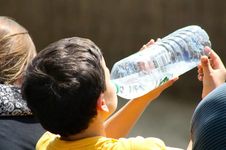 Child drinking water outdoors in hot weather
